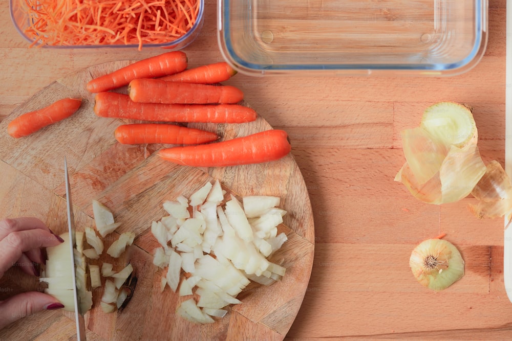 una tabla de cortar cubierta con zanahorias y cebollas