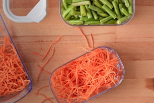 a couple of containers filled with carrots and green beans