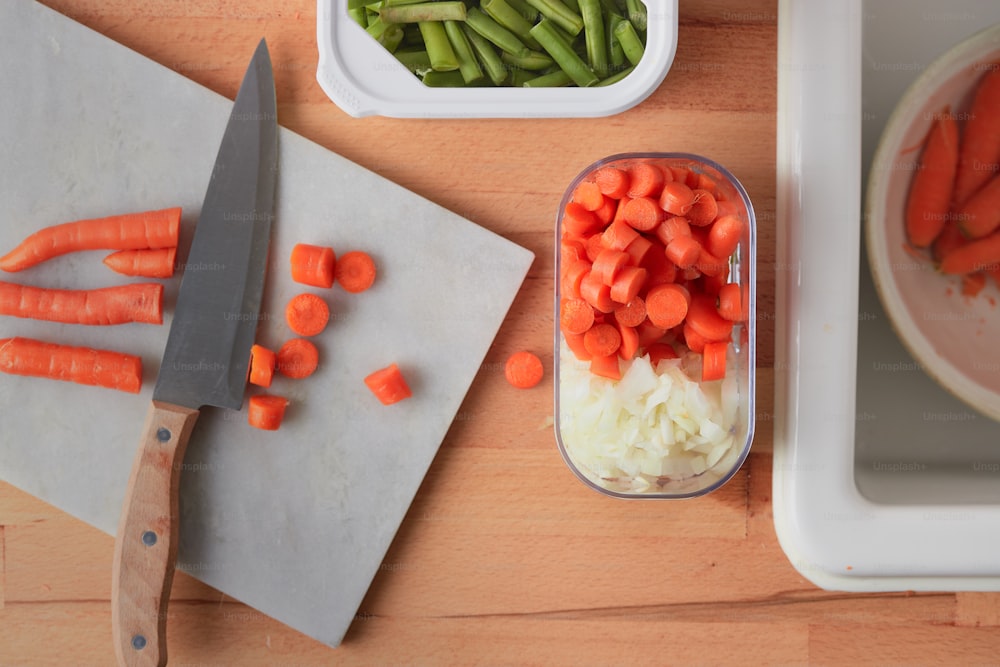 una tabla de cortar con zanahorias, apio y cebollas