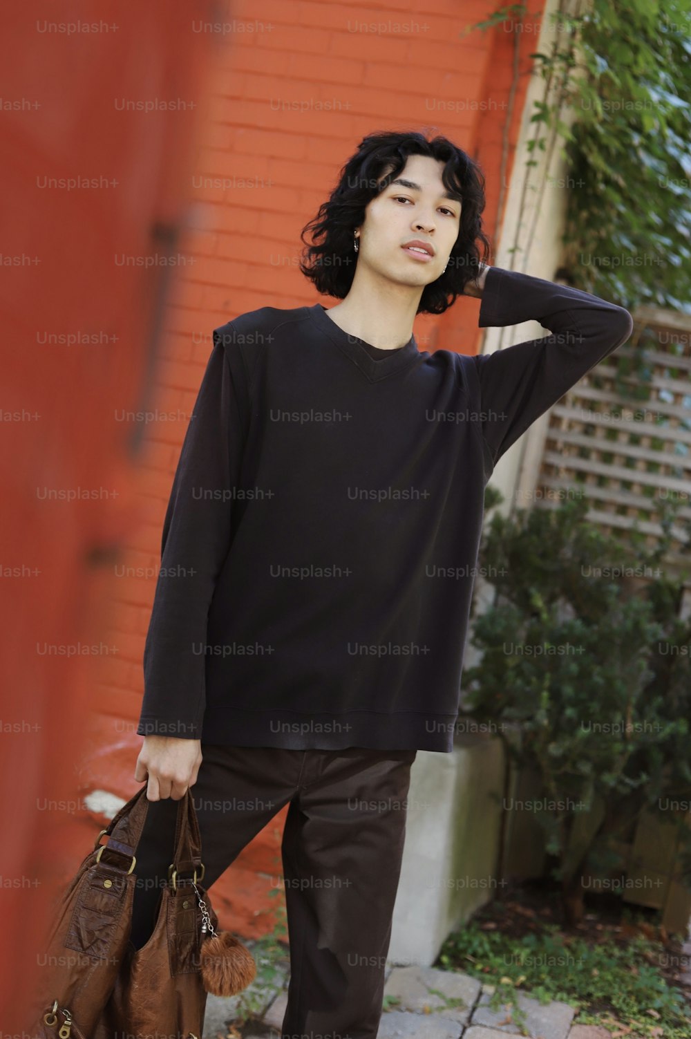 a young man holding a brown bag standing in front of a red building