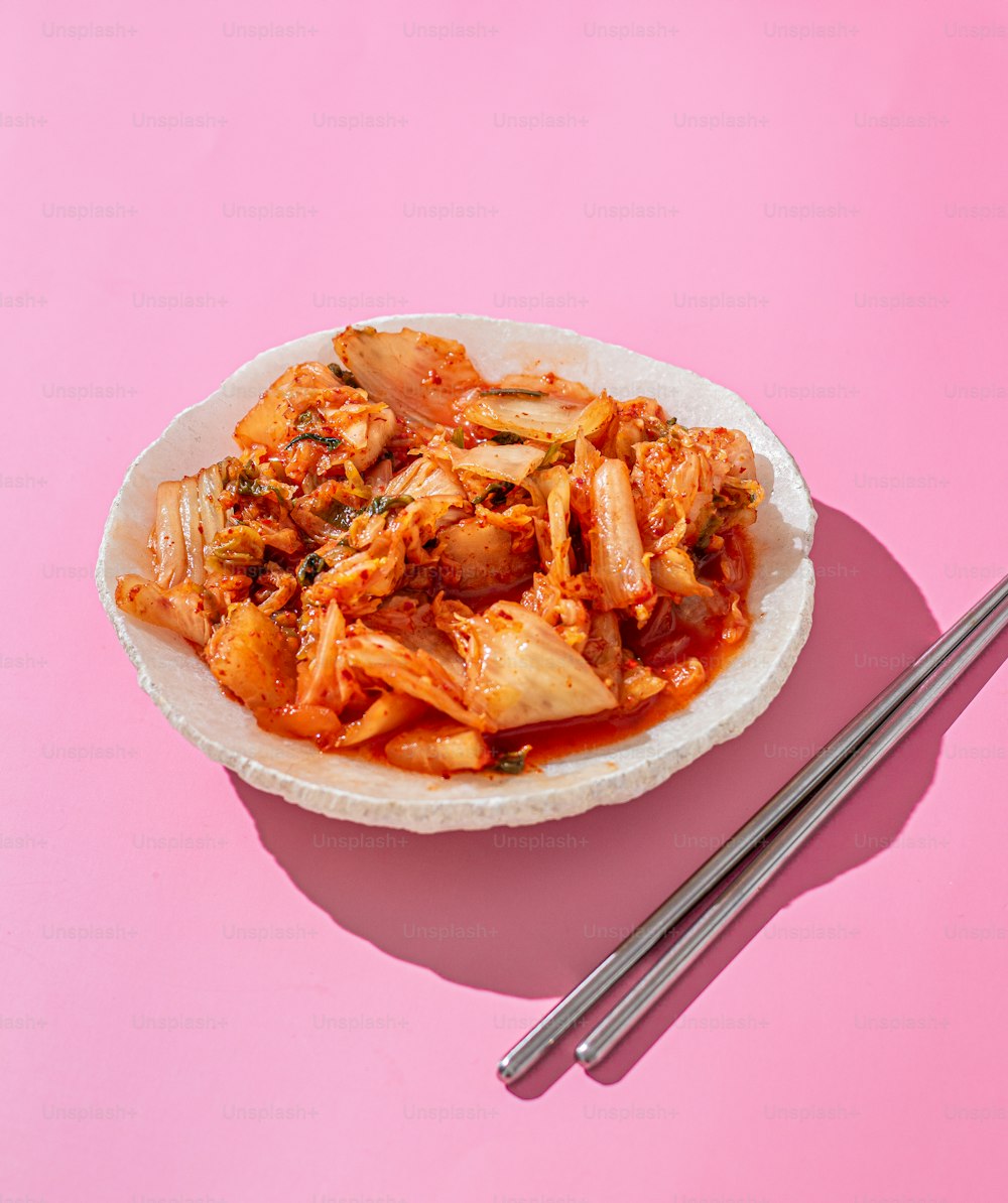 un plato de comida con palillos sobre una superficie rosada