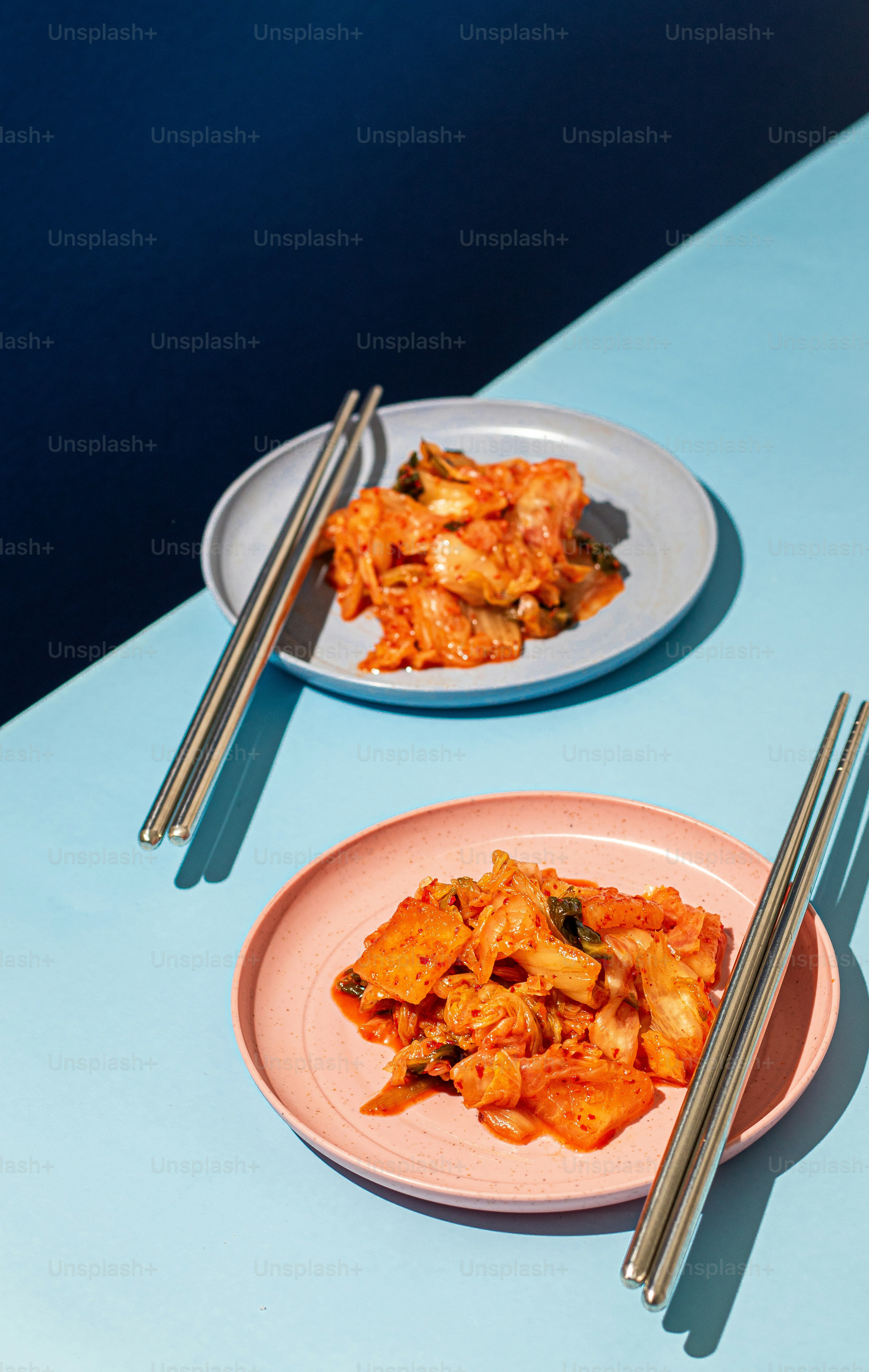 two plates of food with chopsticks on a table