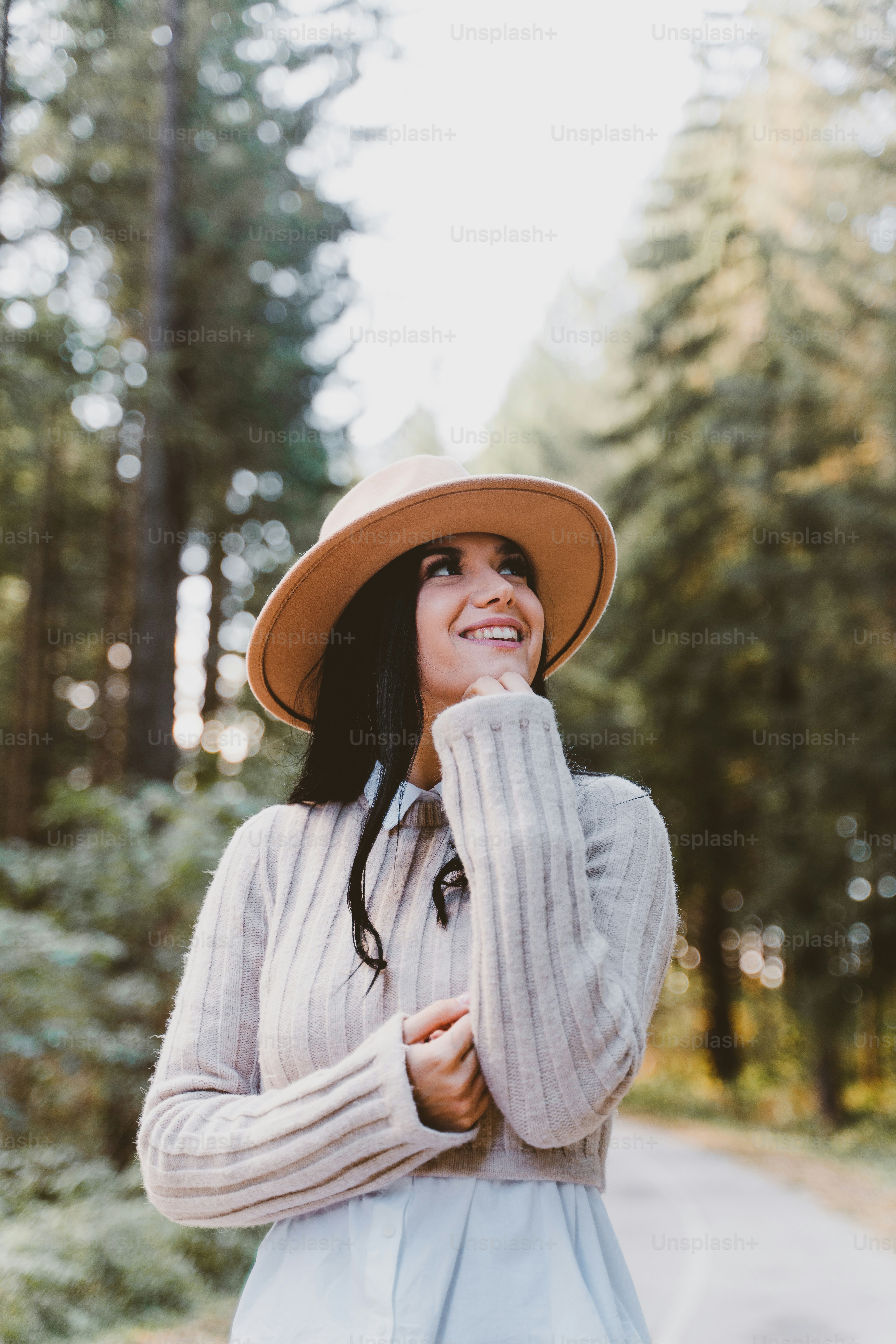 a woman in a hat is standing in the woods