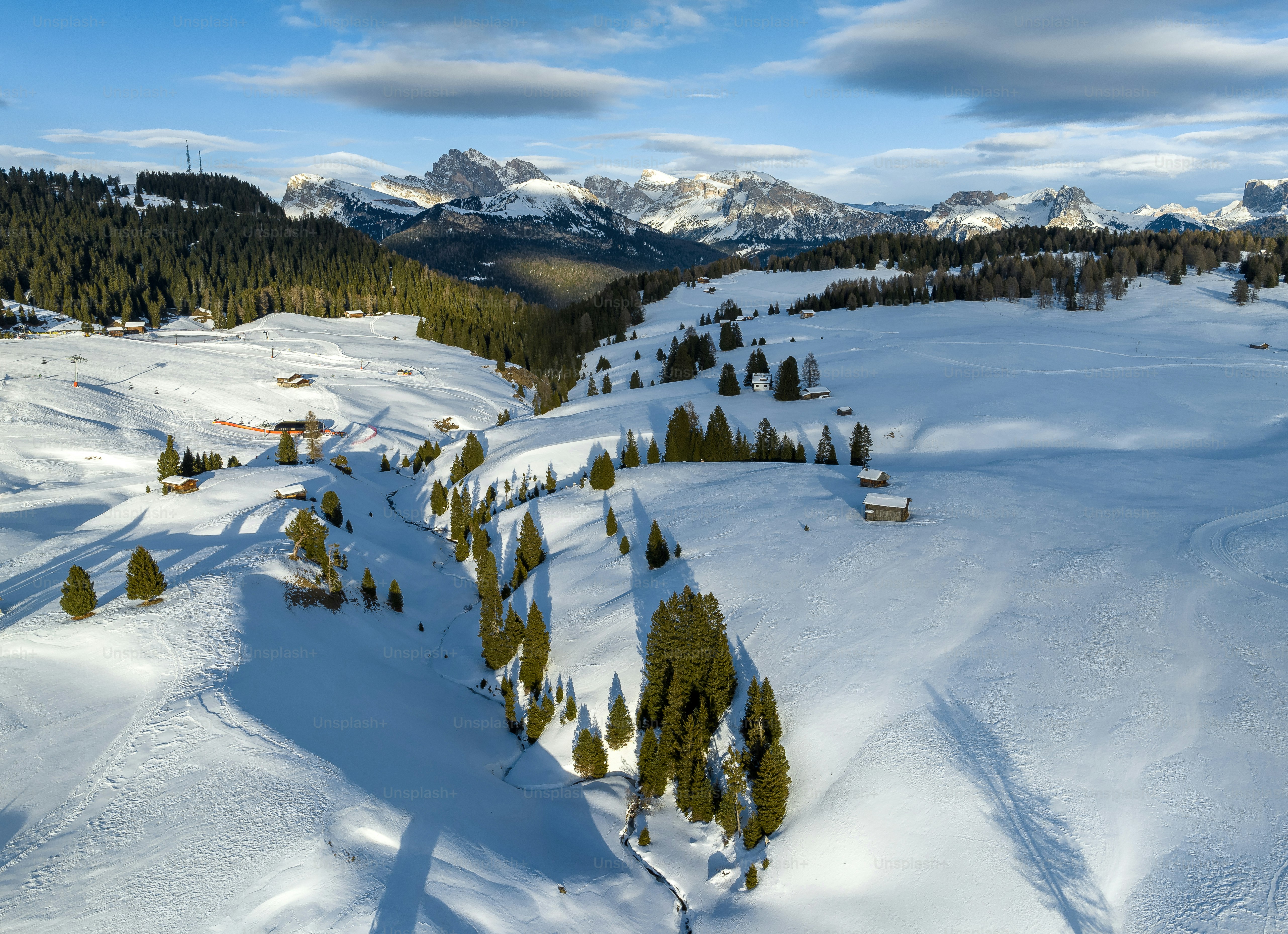 a snow covered ski slope with trees and mountains in the background
