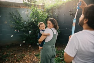 a woman holding a child in her arms and bubbles in the air