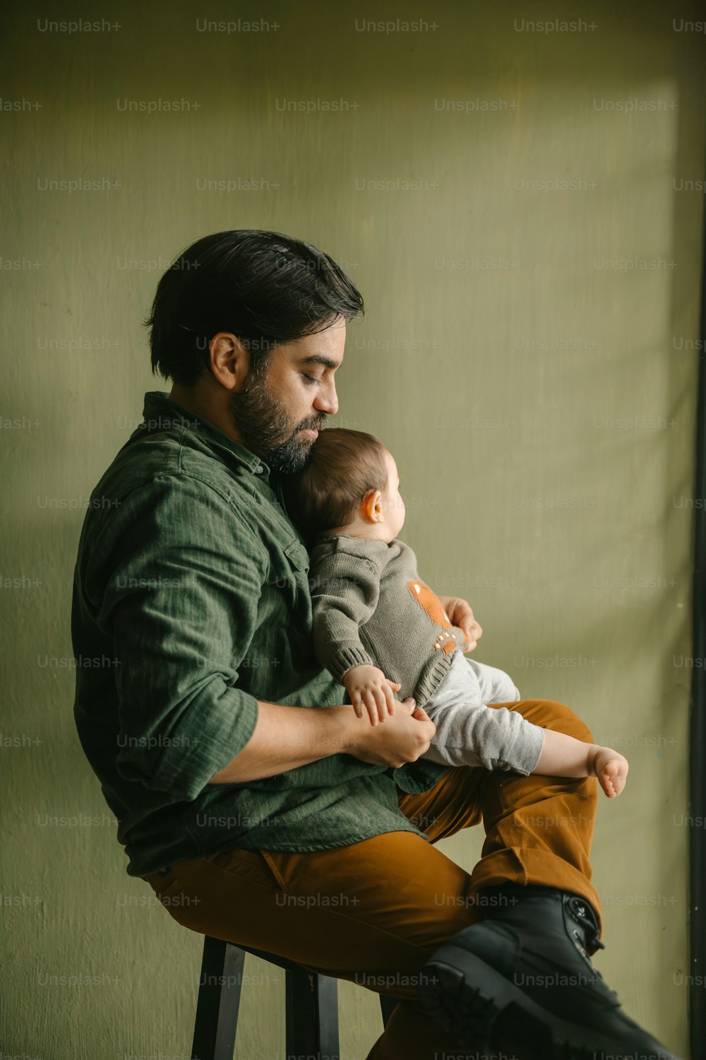 a man sitting on a stool holding a baby