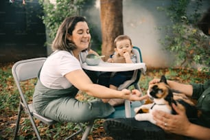 a woman sitting in a chair with a baby and a dog