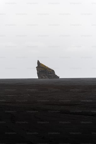 a large rock sitting on top of a black beach