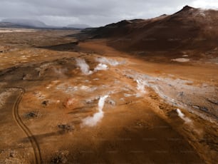 an aerial view of a barren area with steam coming out of the ground