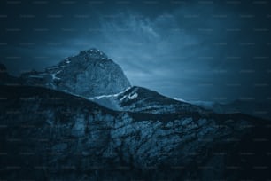 a very tall mountain covered in snow under a cloudy sky