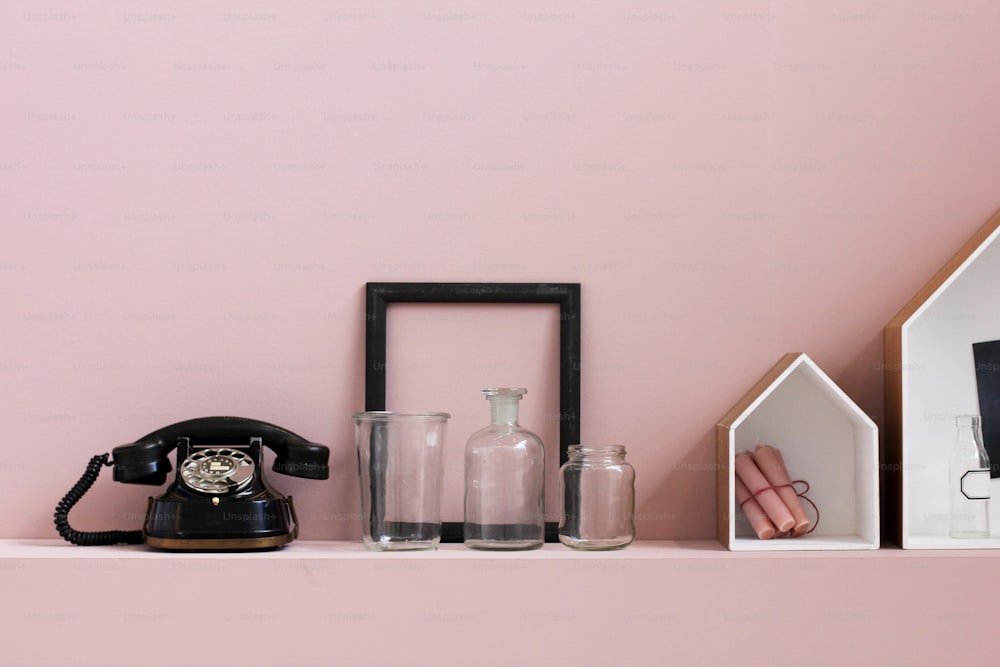 a shelf with a phone, vases, and other items on it