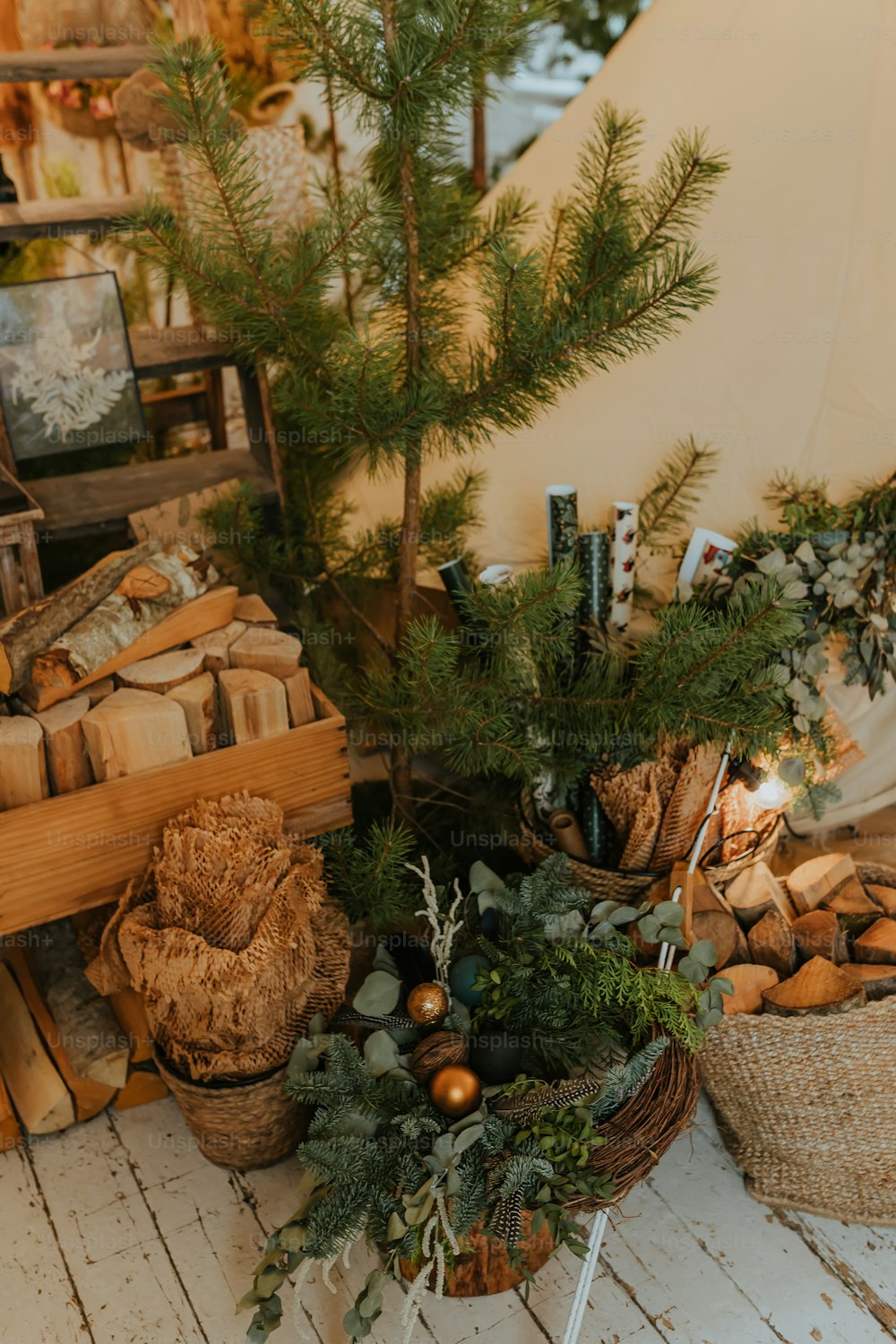 Una mesa con una cesta de troncos y un árbol de Navidad