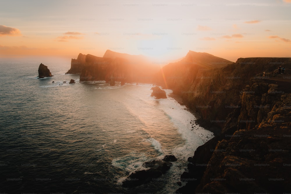 the sun is setting over the ocean and cliffs