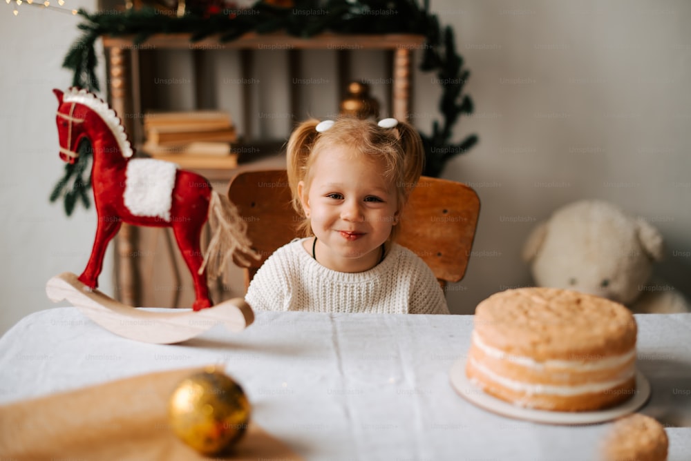 a little girl sitting at a table with a cake