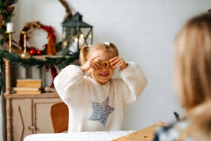 a little girl sitting at a table looking through a pair of glasses