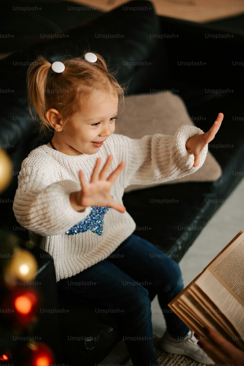 a little girl sitting on a couch holding a book