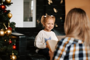 a little girl sitting on a couch reading a book