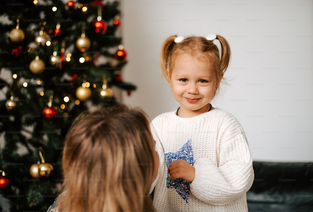 Uma menina ao lado de uma árvore de Natal