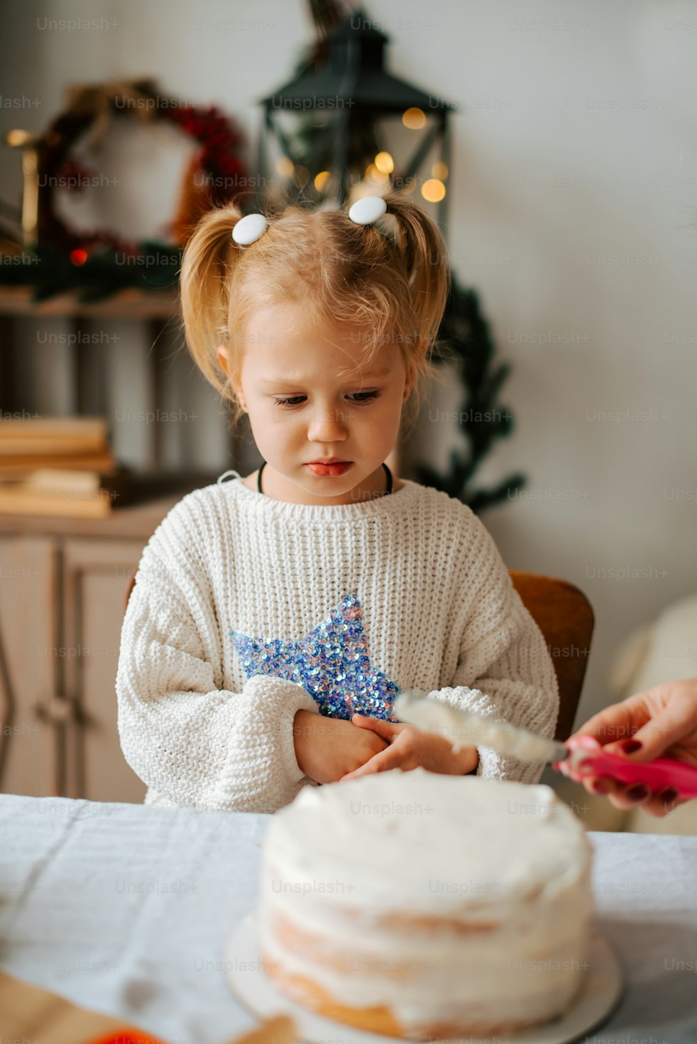 a little girl sitting at a table with a cake