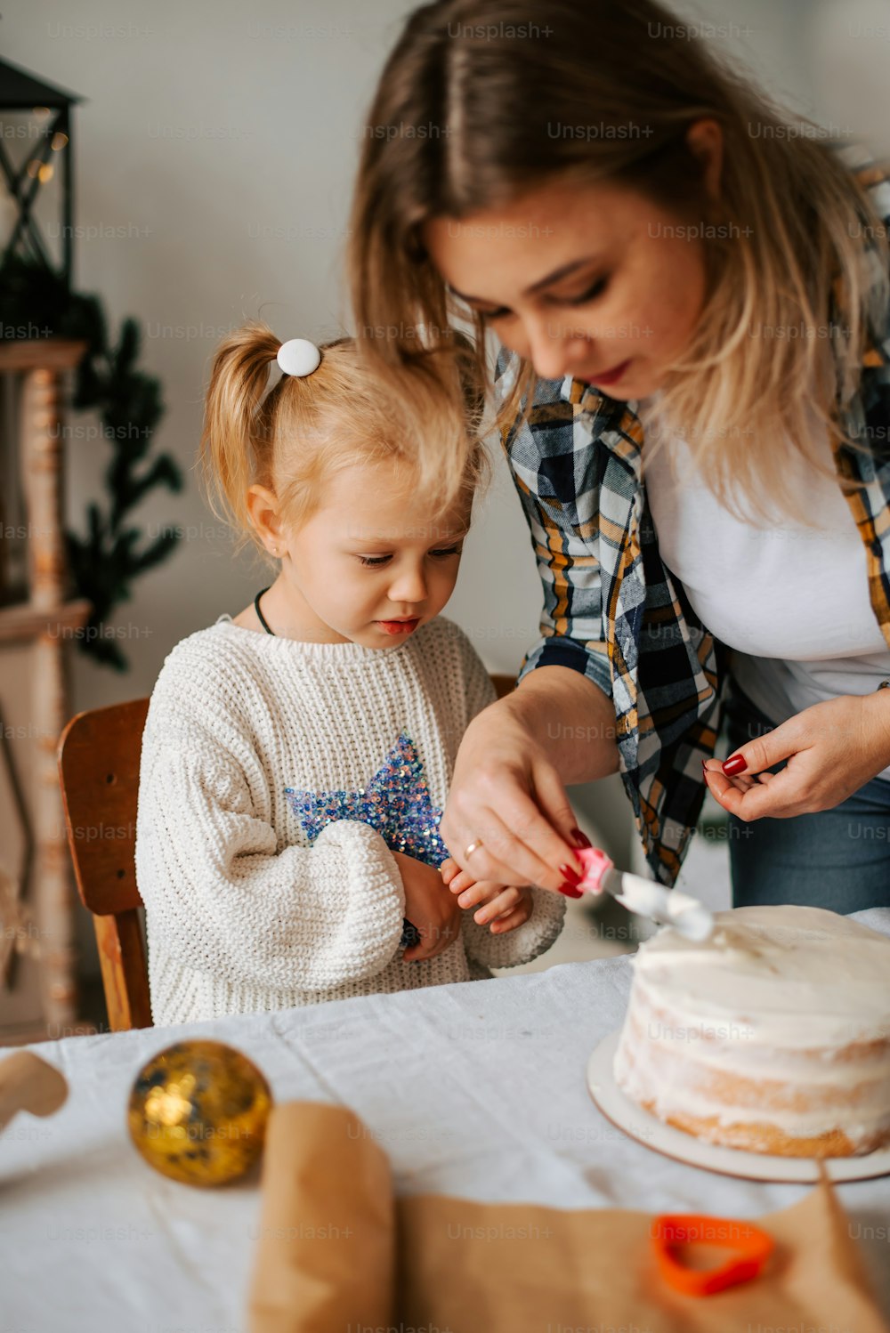a woman and a little girl standing in front of a cake