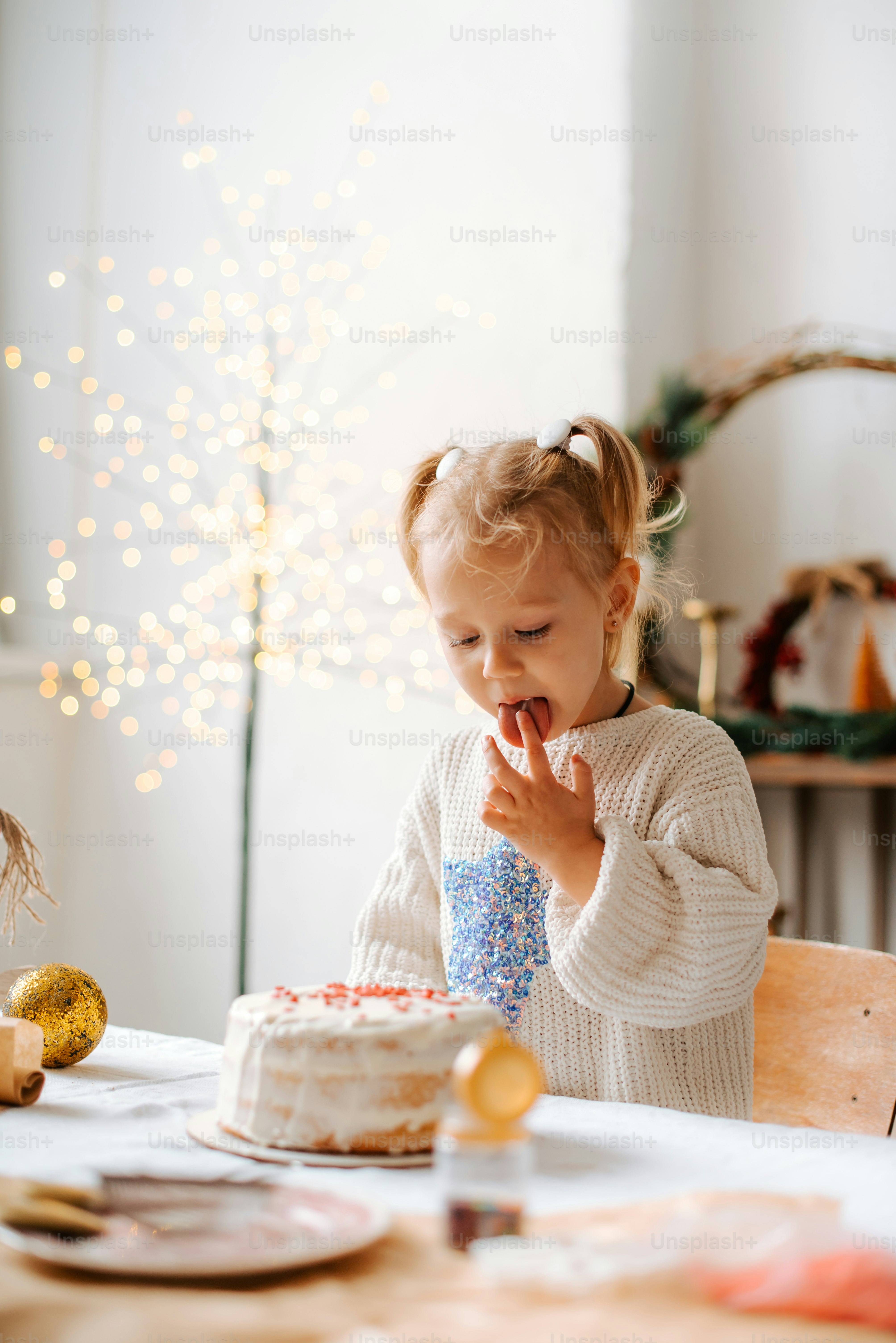 A little girl sitting in front of a cake photo – Sticking out tongue ...