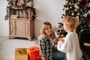 two young girls sitting on the floor near a christmas tree