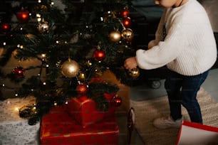 Un niño pequeño de pie junto a un árbol de Navidad