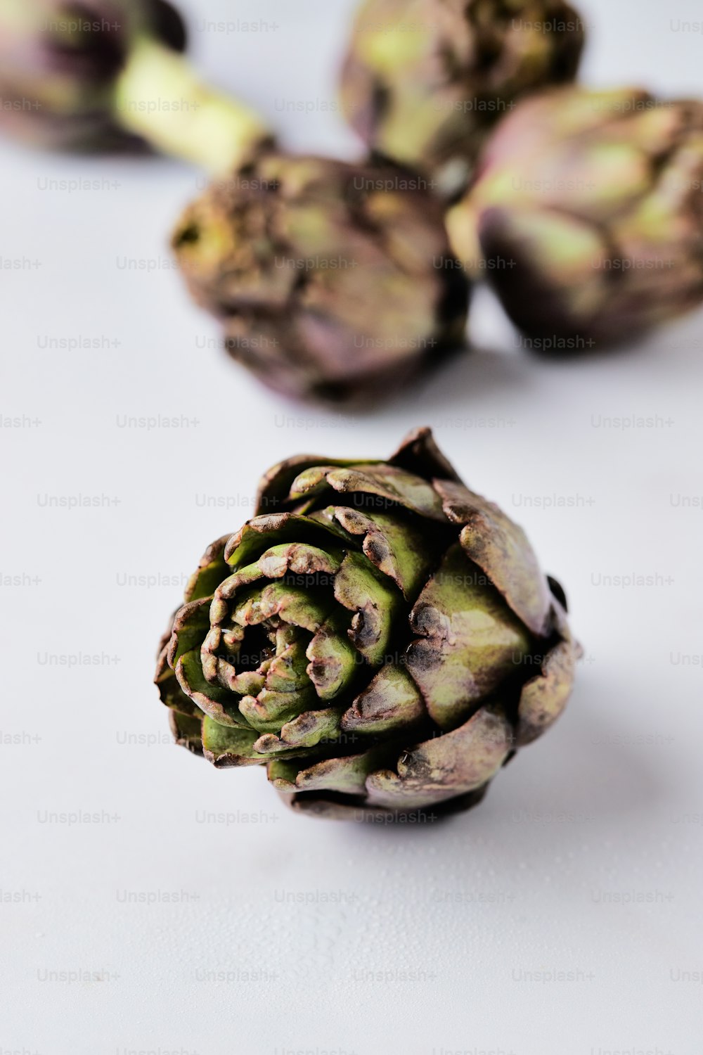 an artichoke on a white surface with other artichokes