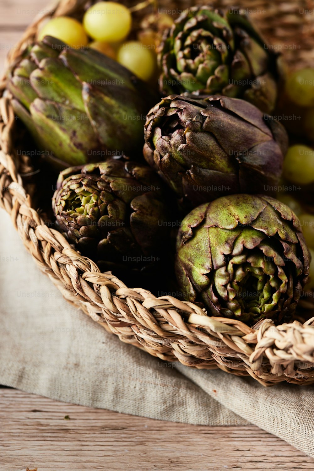 a wicker basket filled with artichokes and grapes