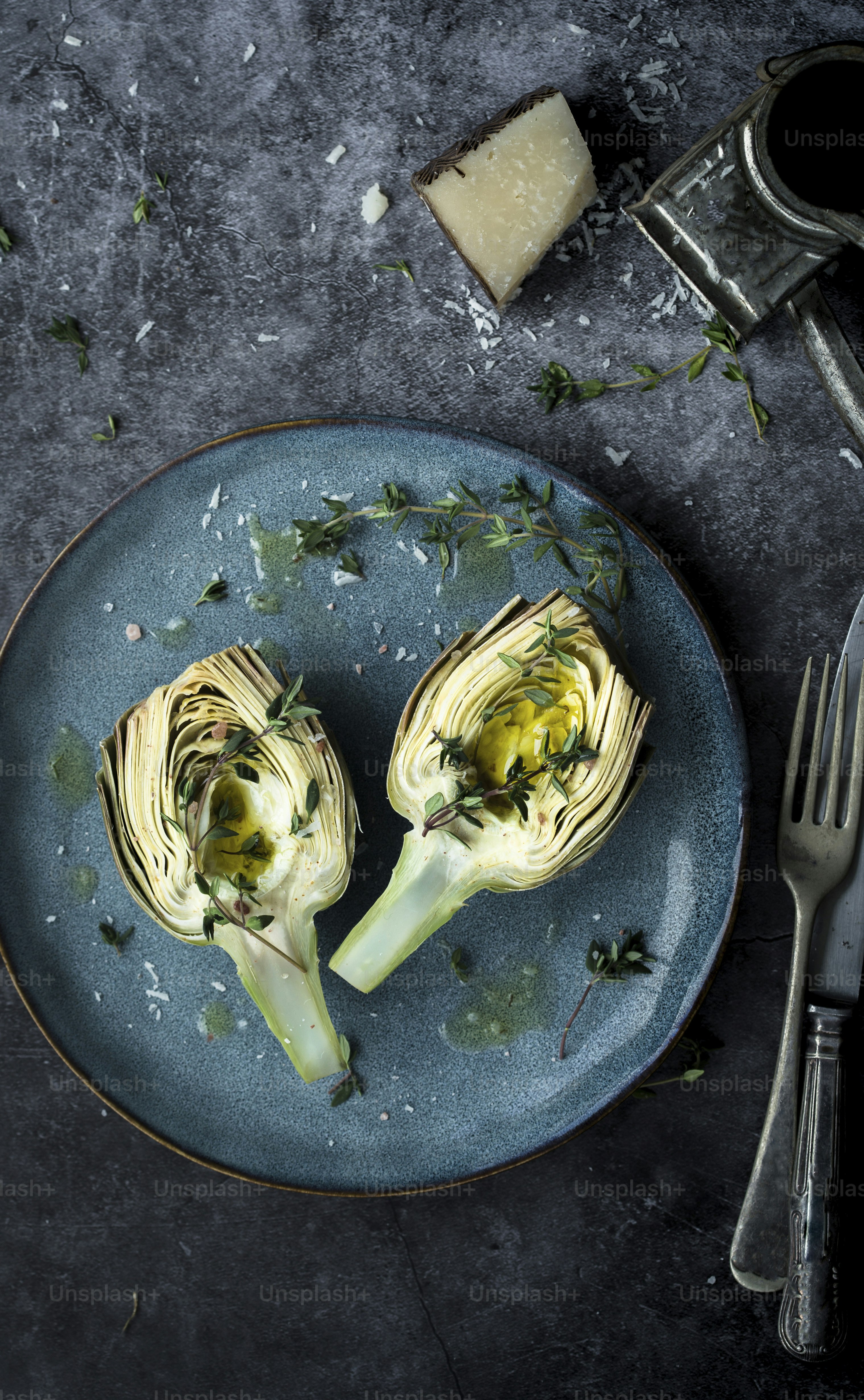a blue plate topped with artichokes next to a knife and fork