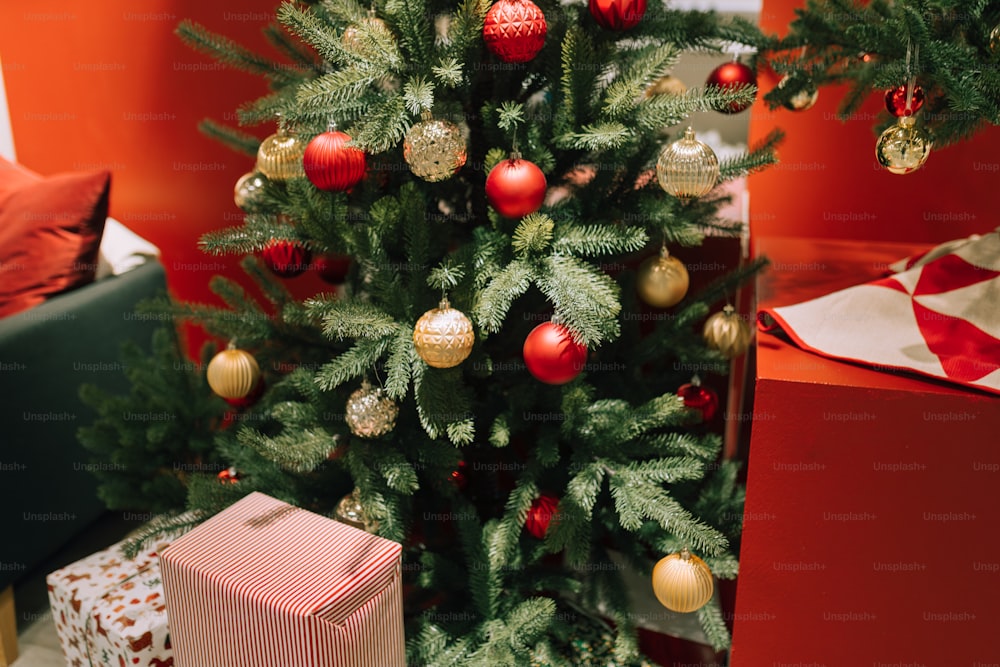 Un pequeño árbol de Navidad con adornos rojos y dorados
