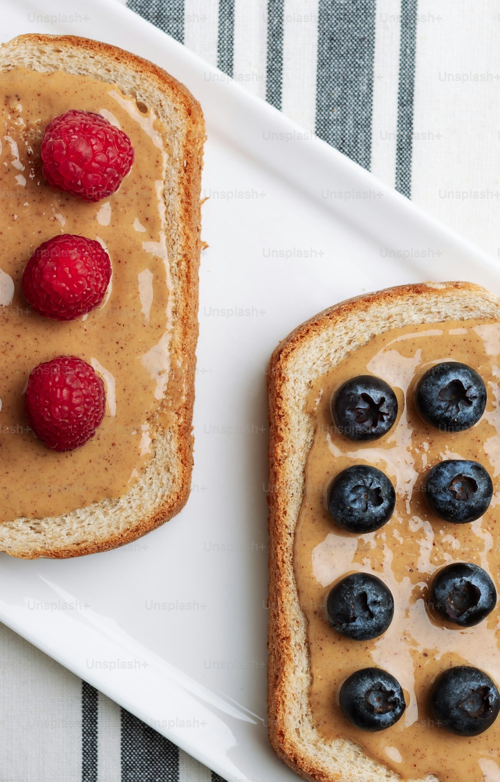 two pieces of bread with peanut butter and berries on them