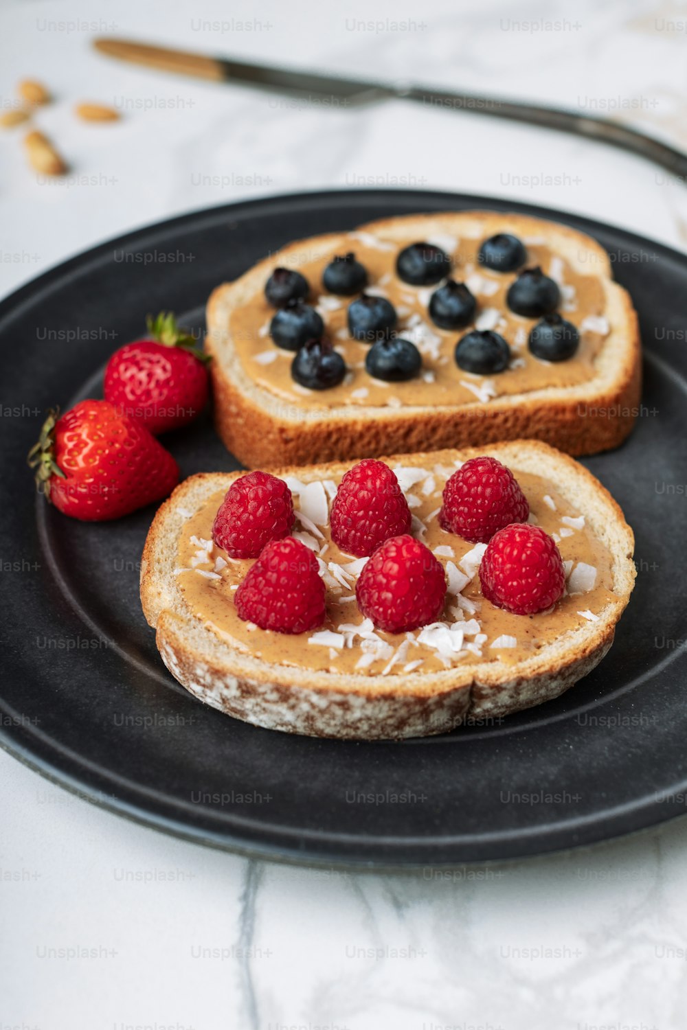 two pieces of toast with berries and coconut on a plate