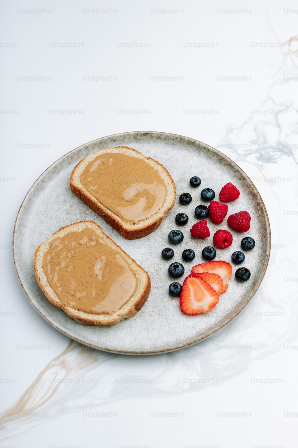 a plate of toast, berries, and peanut butter