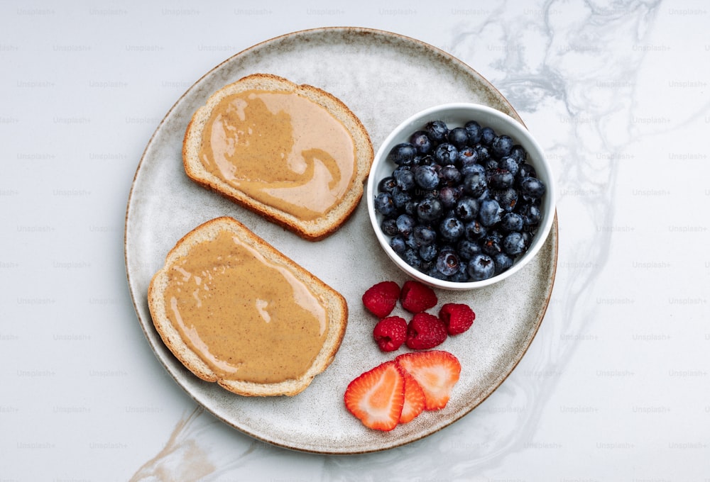 a plate of toast, berries, and a bowl of peanut butter
