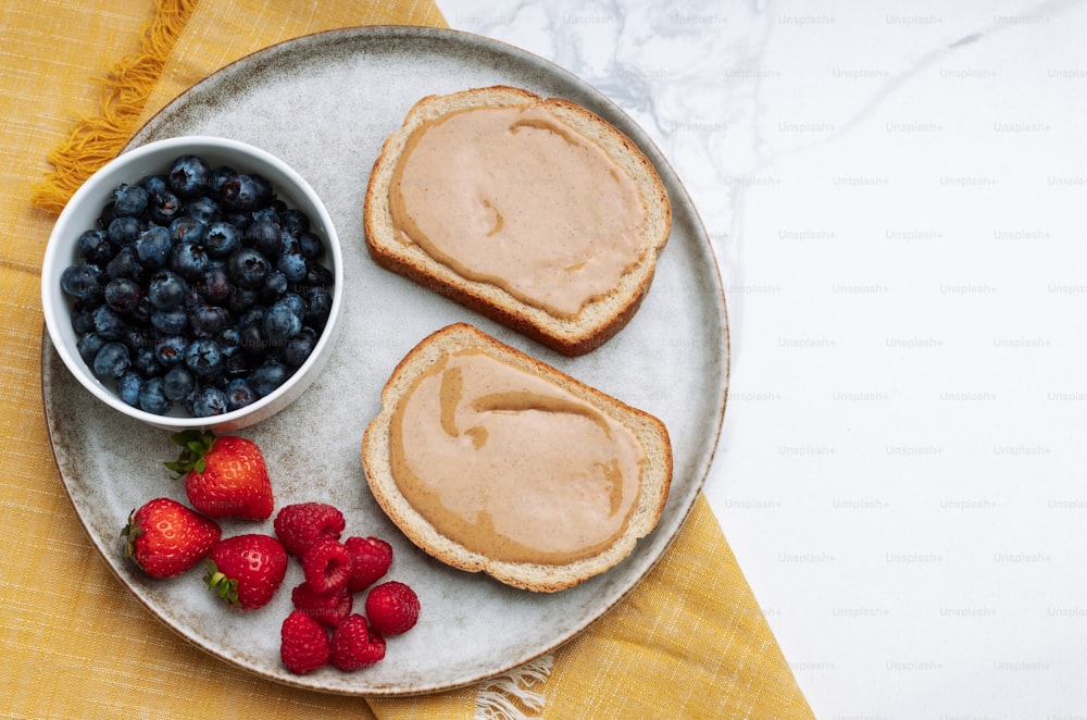 a plate with toast, berries, and peanut butter on it