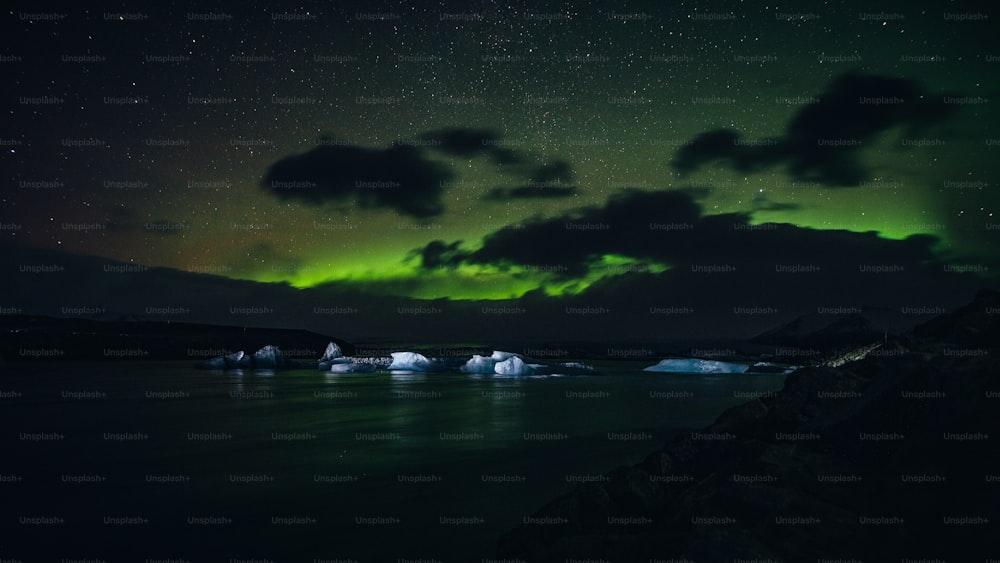 a green and white aurora over a body of water