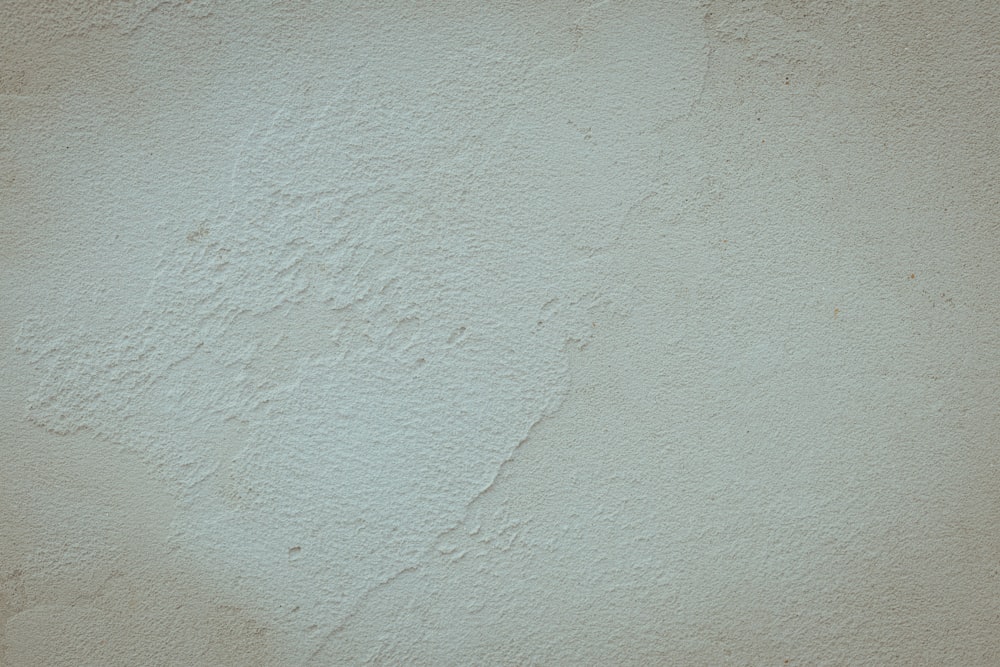 a white stucco wall with a black clock on it