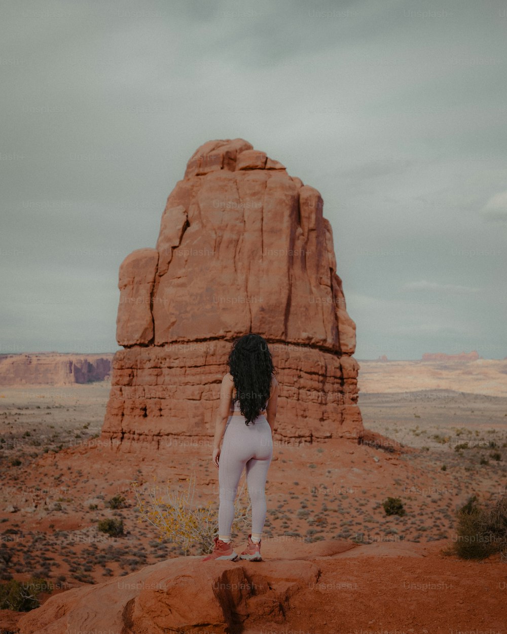 uma mulher em pé no topo de uma formação rochosa