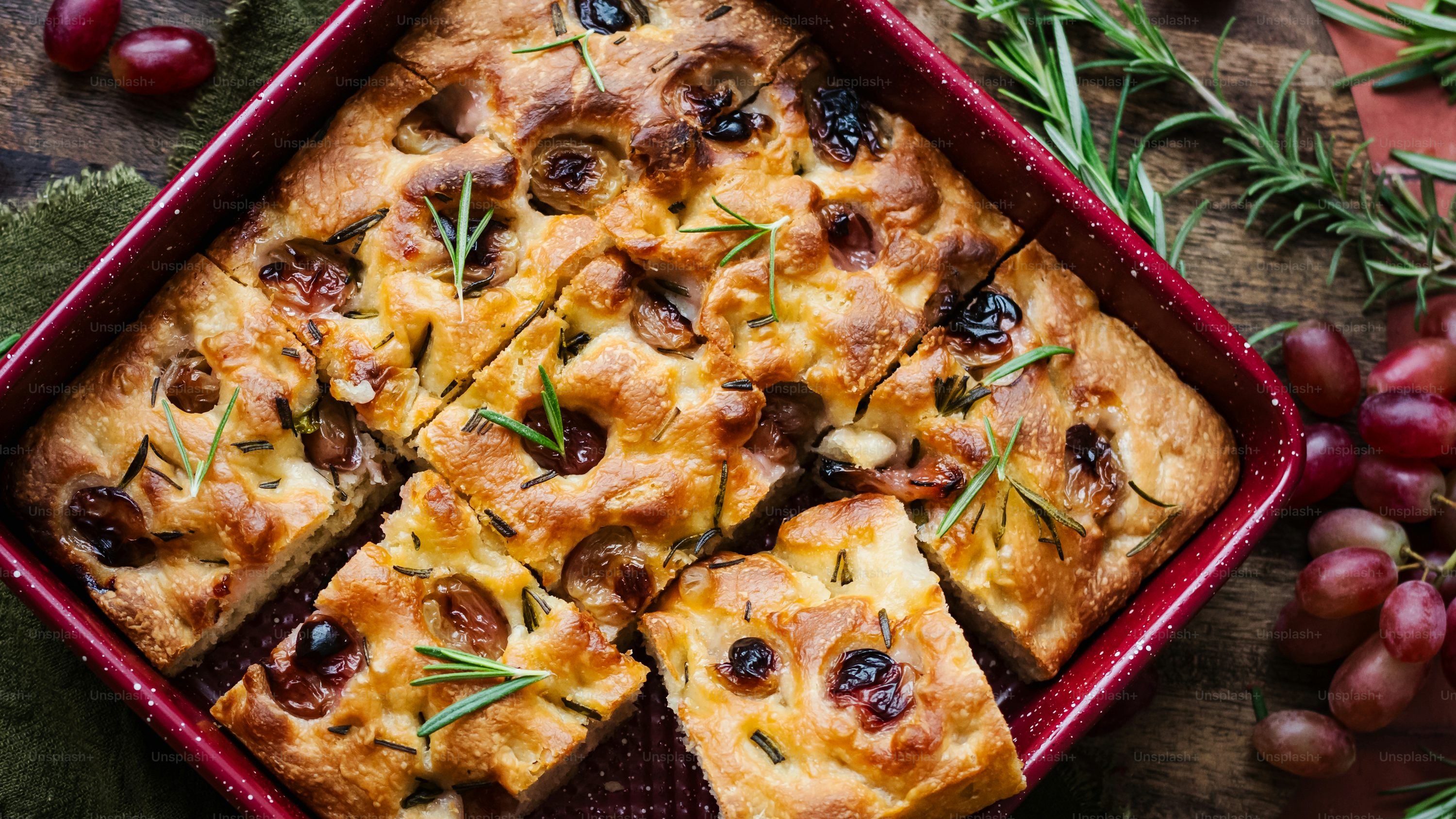 a casserole with olives and rosemary in a red dish