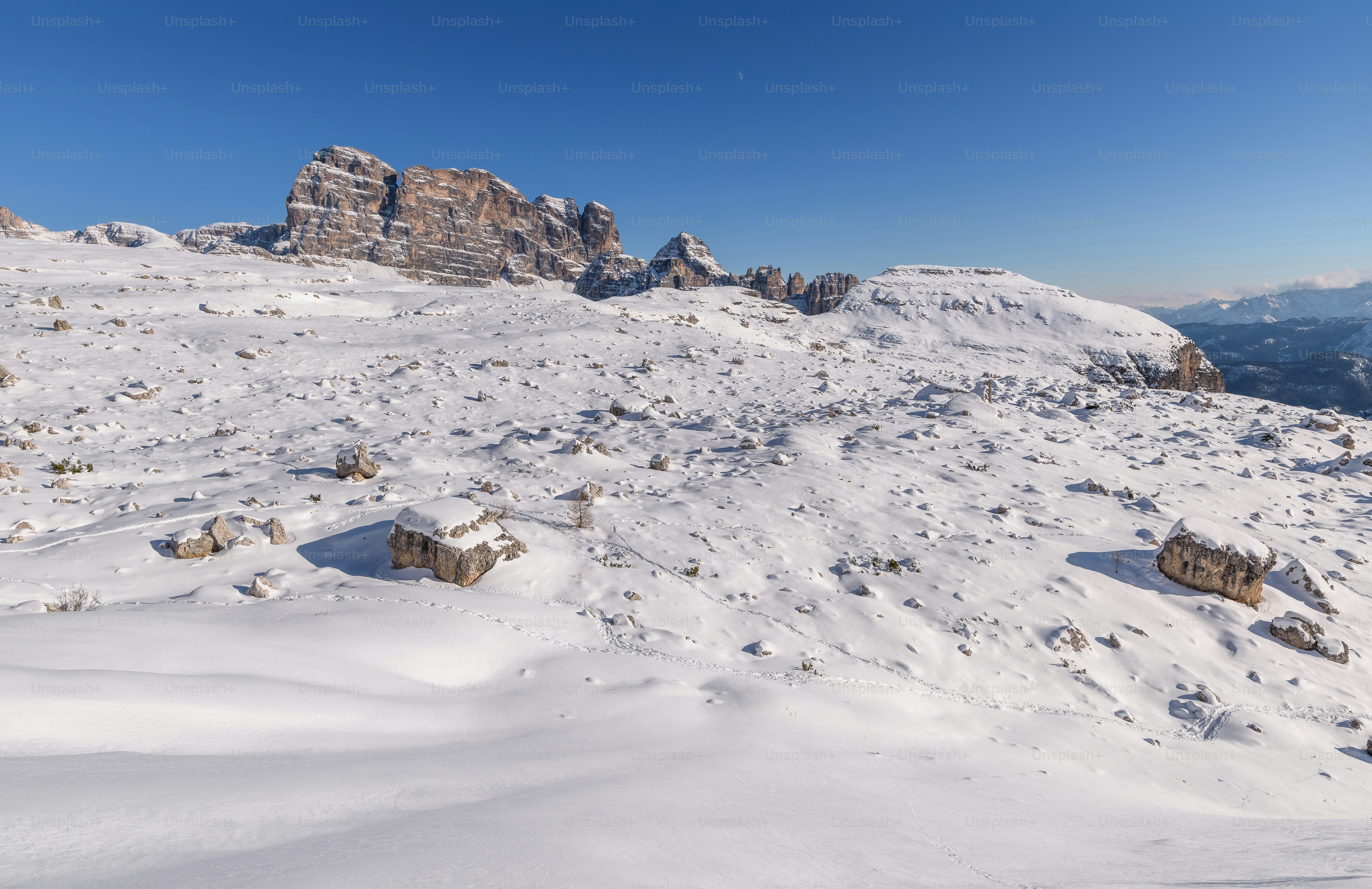 A snow covered mountain with rocks and a sky background photo ...