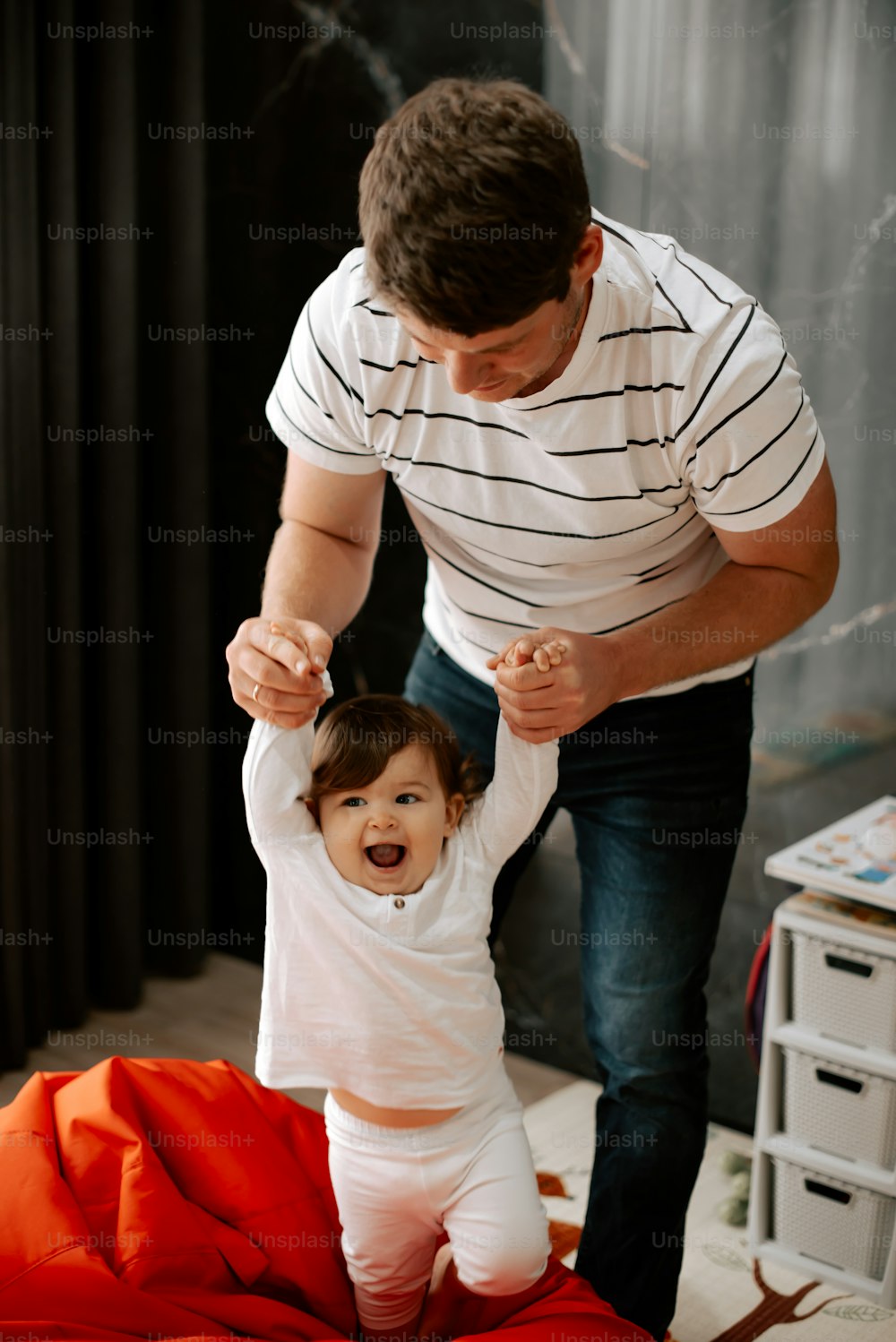 a man holding a baby's hand while standing on a bed