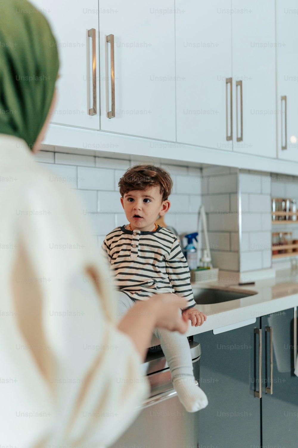 a little boy sitting on top of a kitchen counter