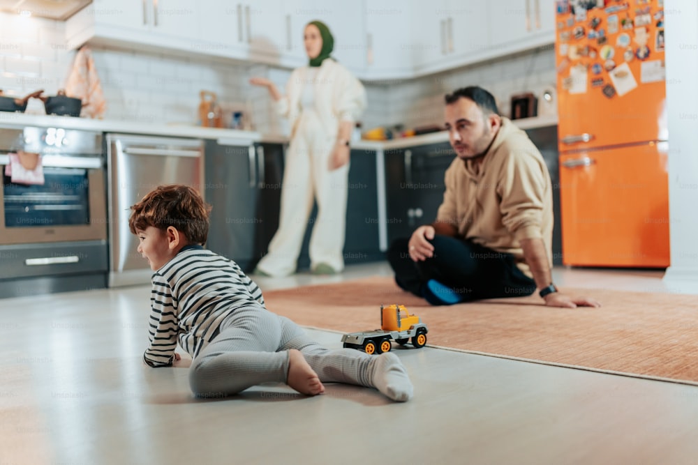 a little boy sitting on the floor playing with a toy truck