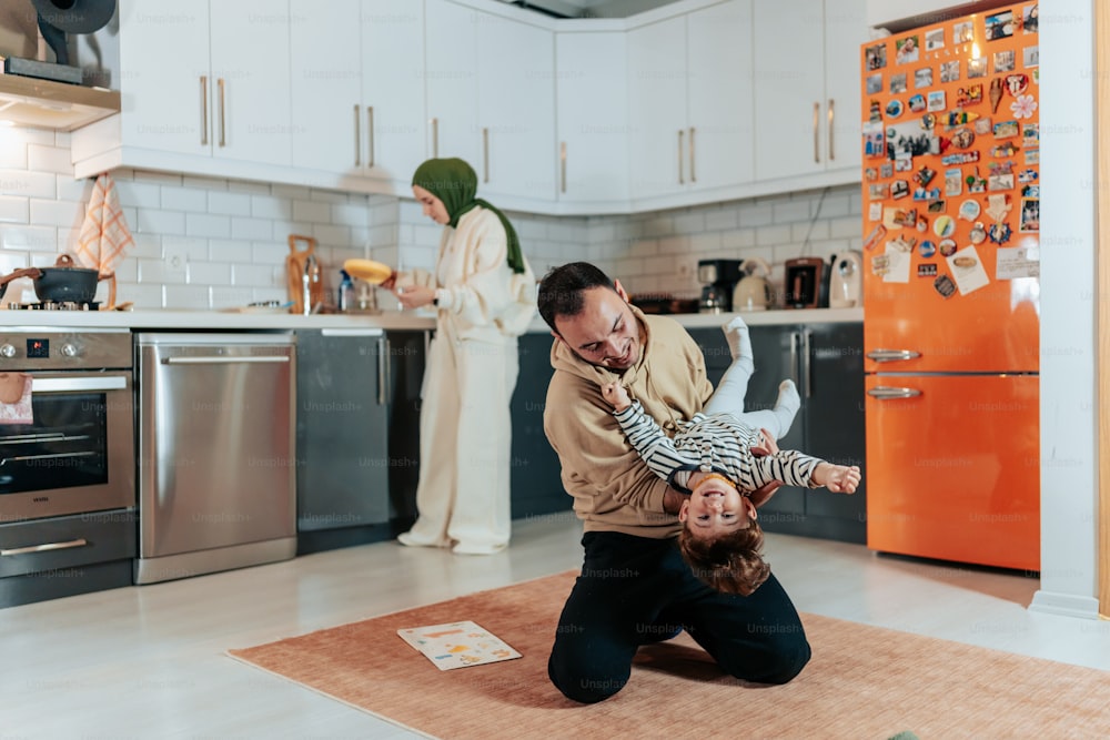 ein Mann hält ein Kind in einer Küche