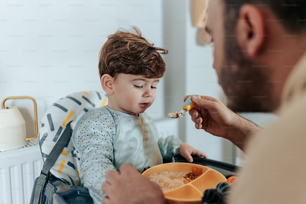 a man feeding a child a spoon of food