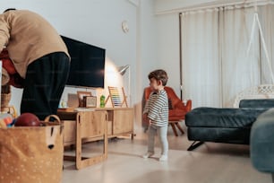 a little girl standing in a living room next to a man