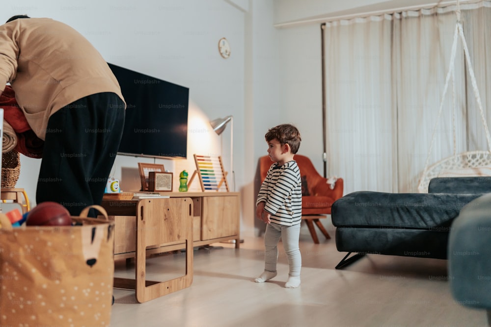 a little girl standing in a living room next to a man