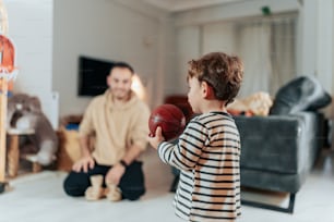 a young boy holding a basketball in front of a man