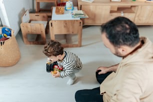 Un hombre sentado en el suelo jugando con un niño pequeño